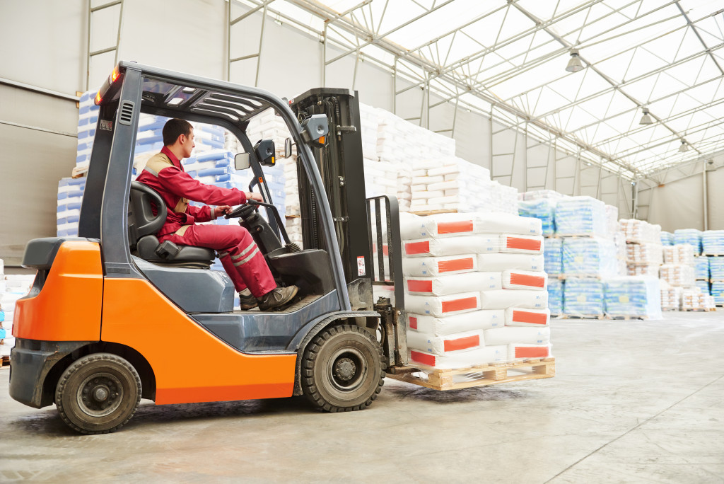 worker in red driving a forklift to deliver materials in a warehouse