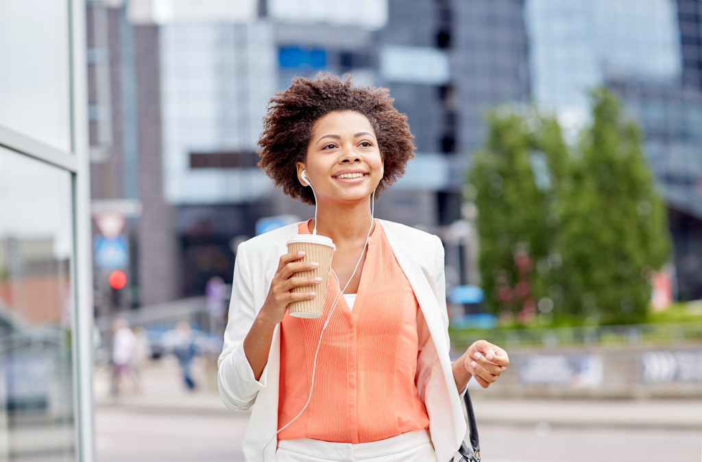 happy female business owner walking with headset on holding a coffee